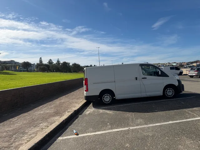 The parked All City Services van in front of a beautiful beach