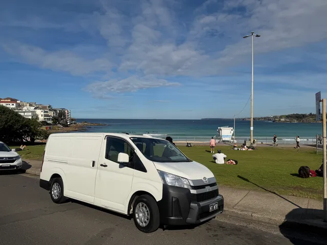 The parked All City Services van in front of a bondi beach